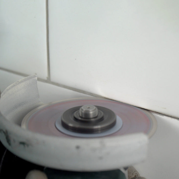 Worker using Cleaner 4 inch diamond blade on angle grinder to clean grout