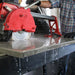 Red circular saw in use on a metal surface with a person partially visible.