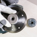 Close-up of a brake disc with gloves and another brake component on a white background