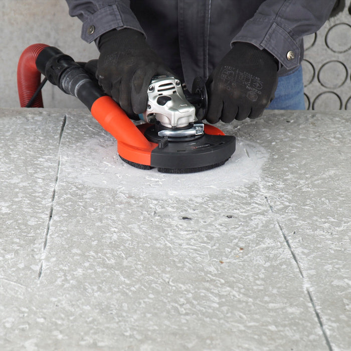 Contractor grinding concrete indoors with VORTEX dust guard attached to shop vac